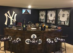 a bar with stools and bottles on it in a room that has baseball memorabilia