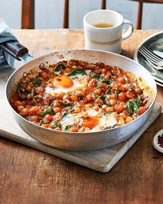 a pan filled with eggs and vegetables on top of a wooden table