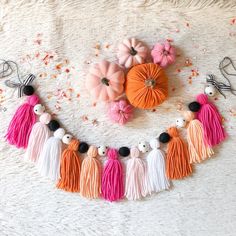 an orange, pink and white tasseled necklace with pumpkins on it next to other decorations