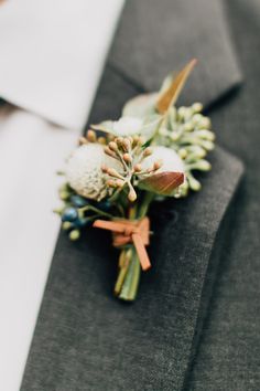 a boutonniere is adorned with flowers and leaves on a man's lapel