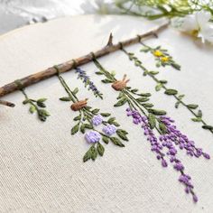 a close up of a cross stitch pattern on a piece of cloth with flowers and twigs