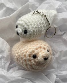 two crocheted teddy bears sitting on top of each other, one with a keychain