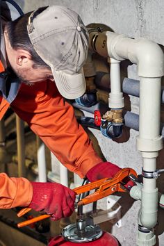 a man in an orange jacket working on pipes