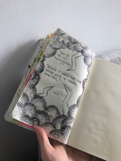 someone is holding up an open book with drawings on it