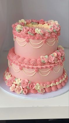 a three tiered cake with pink frosting and flowers