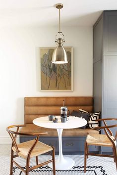 a kitchen table with chairs and a bench in front of the counter top, next to a painting on the wall