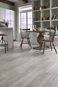 a dining room with wood floors and green walls is pictured in this image, there are two chairs at the table