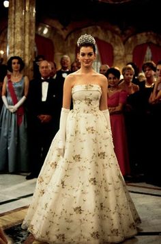 a woman in a white dress standing next to other people and wearing tiaras