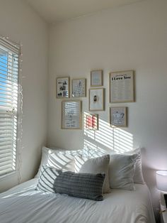 a bedroom with white walls and pictures on the wall above the bed, along with pillows