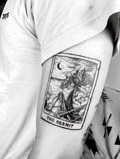 a black and white photo of a man's arm with a tarot card tattoo on it