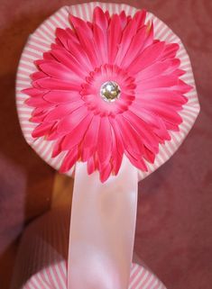 a pink flower sitting on top of a white plate with a bow around it's neck