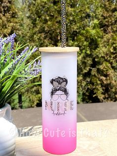 a pink and white vase sitting on top of a wooden table next to a plant