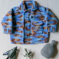 a crocheted jacket and toy airplane on a table