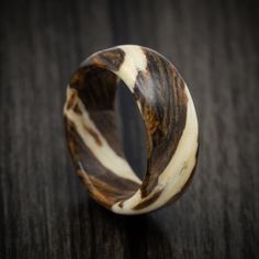 a wooden ring with white and brown stripes on it sitting on a wood table next to a black background