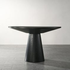 a black table sitting on top of a tiled floor next to a white wall in an empty room