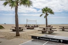 there is a ping pong table on the beach with palm trees in the background