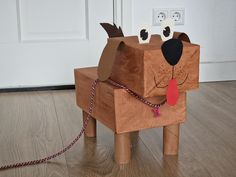 a dog made out of cardboard sitting on the floor next to a door with a leash