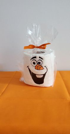 a bag with a face drawn on it sitting on top of an orange tablecloth