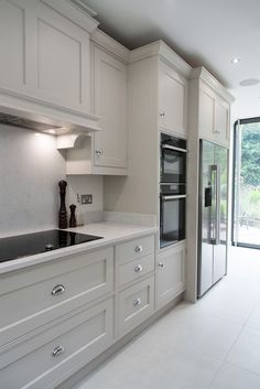 a kitchen with all white cabinets and an open glass door leading to the outside patio