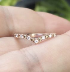 a hand holding a gold ring with three diamonds on it's side and the top half