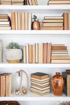 many books are on the shelves with vases and other items in front of them