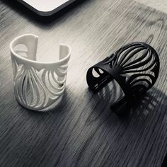 two white vases sitting on top of a wooden table next to a laptop computer