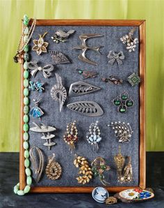 a wooden frame filled with lots of different types of brooches and earrings on top of a table