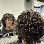 a woman sitting in front of a mirror with her hair styled to look like an afro