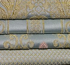 four different types of fabric are stacked on top of each other, one is blue and the other has gold