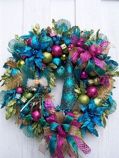 a christmas wreath with ornaments hanging from it's side on a white wooden wall