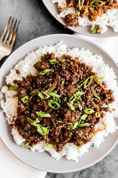 two plates filled with meat and rice on top of a white plate next to a fork