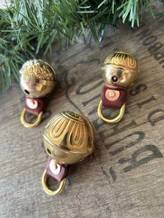 three antique brass door knobs on a wooden surface with pine branches in the background