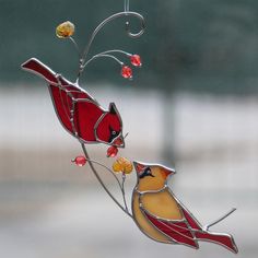 two stained glass birds on a branch with red berries hanging from it's side