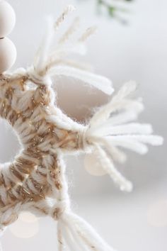 an ornament made out of twine and yarn with white balls on it