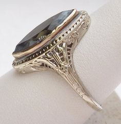 A beautiful ring from the Art Nouveau period. This ring features a man made marquise shape blue stone. Stone does have a scratch on the table. The marquise stone is bezel set in a beautiful filigree mounting. All the detail of the mounting is in excellent condition. The marquise stone measures approximately 17.5 x 7.25 mm. This piece is 18 karat white gold and weighs 4.0 grams. Ring is currently a size 10 3/4. Marquise White Gold Sapphire Ring, White Gold Marquise Sapphire Ring, Elegant Marquise Cut Ring With Bezel Setting, Marquise Sapphire Ring With Diamond Cut For Anniversary, Antique Silver Marquise Jewelry, Vintage Marquise Silver Jewelry, Vintage Silver Marquise-shaped Jewelry, Vintage Silver Marquise Jewelry, Antique Marquise Rings For Formal Occasions