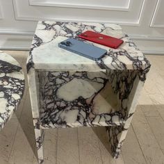 two marble side tables with one red phone on top and the other blue in between