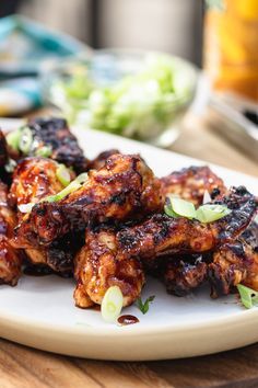 chicken wings on a plate with celery and other food items in the background