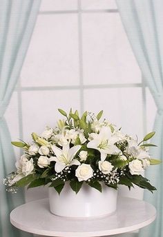 a white flower arrangement sitting on top of a table