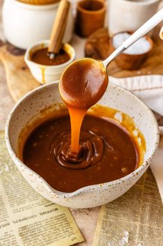 a spoon full of caramel sauce being poured into a bowl