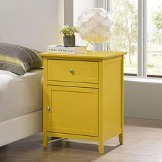 a bright yellow nightstand table next to a bed