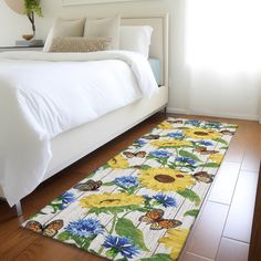 a white bed sitting next to a window on top of a hard wood floor