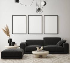 a modern living room with black couches and three framed pictures hanging on the wall