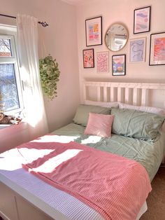 a bedroom with pink and green bedding and pictures on the wall over the bed