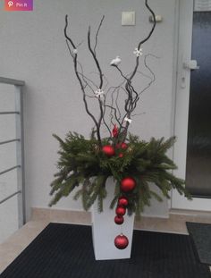 a white vase filled with christmas decorations on top of a black mat next to a door