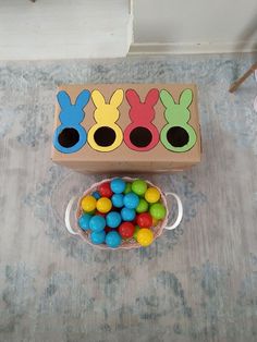 a wooden box filled with colorful candies on top of a table next to a bowl of chocolate eggs