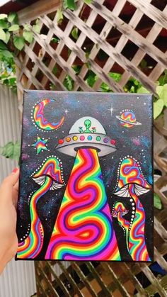 a hand holding up a box with an image of aliens in the sky on it