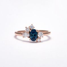 an oval blue and white diamond ring with three smaller diamonds on the band, set in 18k rose gold