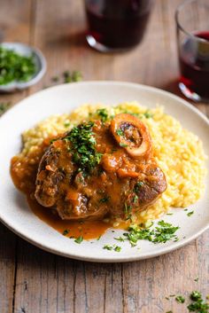 a white plate topped with meat and gravy covered in sauce next to rice