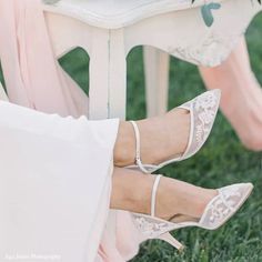 the bride's shoes are white with lace on them and they are sitting on a bench