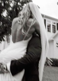 black and white photograph of a woman carrying a man on her back in front of a house